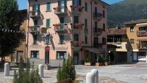 A multi-story building with balconies, a stop sign, and a bar named "Albergo Centro Ristorante Bar". - Albergo Centrale (Fino del Monte)