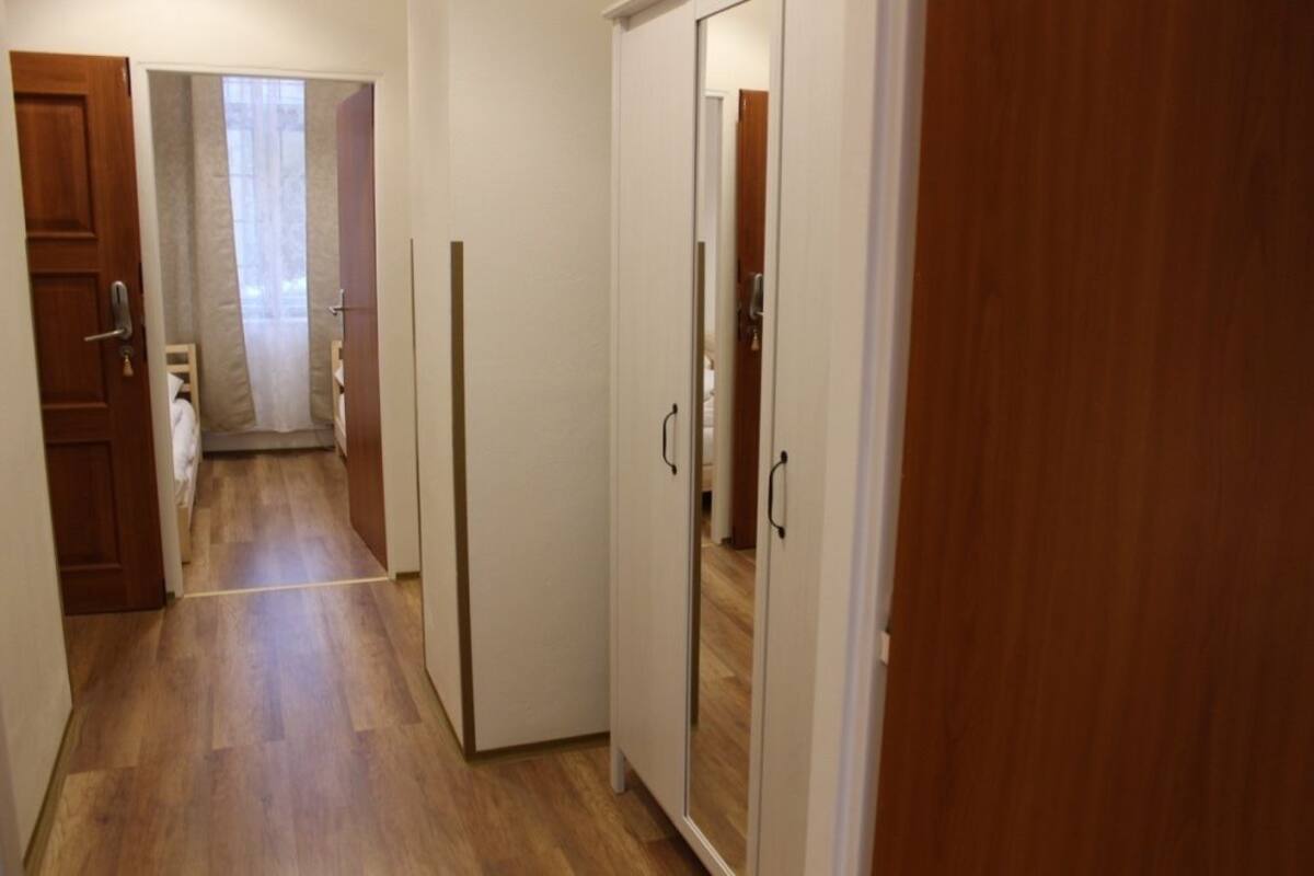 A hallway with wooden flooring, a door, and a mirror on the wall.