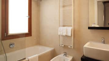 Un baño con bañera, lavamanos, bidé y un perchero para toallas.