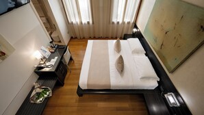 A hotel room with a bed, bedside table, lamp, and a painting on the wall. - Ca' Pozzo Inn (Venice)
