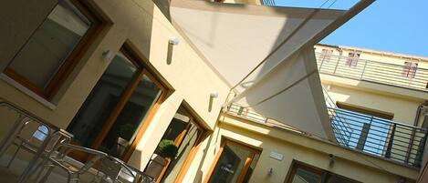 Un bâtiment doté d’un balcon, d’un espace extérieur aménagé pour s’asseoir et d’une grande auvent.