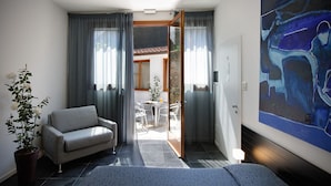 A modern room with a grey sofa, a potted plant, and a painting on the wall. - Ca' Pozzo Inn (Venice)