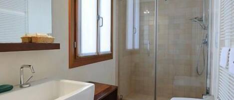 A bathroom with a large mirror, two sinks, a shower, and wooden beams on the ceiling.