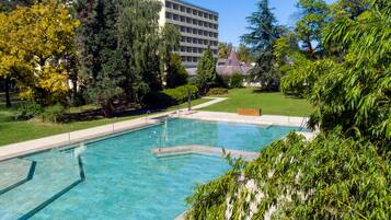 Una piscina rectangular con agua azul cristalina, rodeada por una terraza pavimentada.