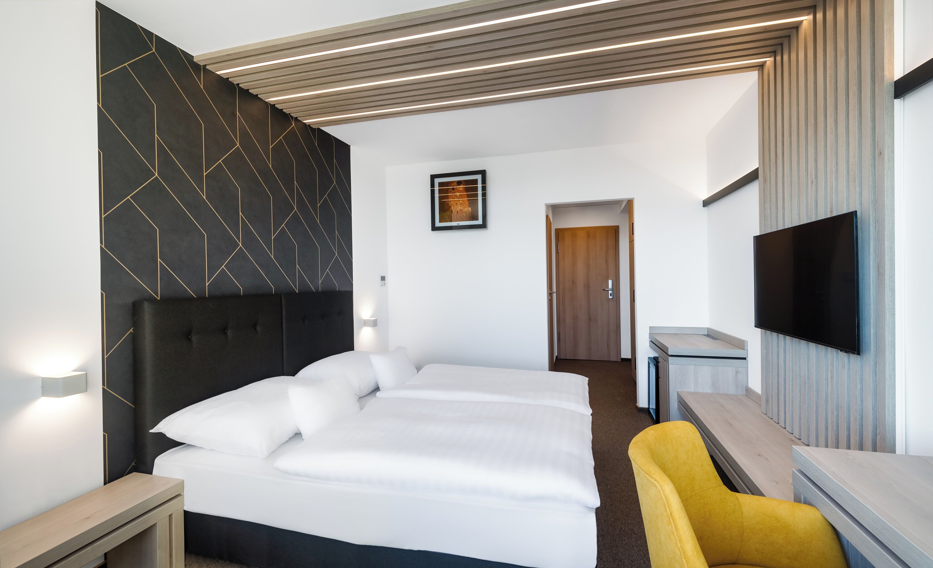 A hotel room with a large bed, a bedside table, a chair, a TV, and a picture on the wall.