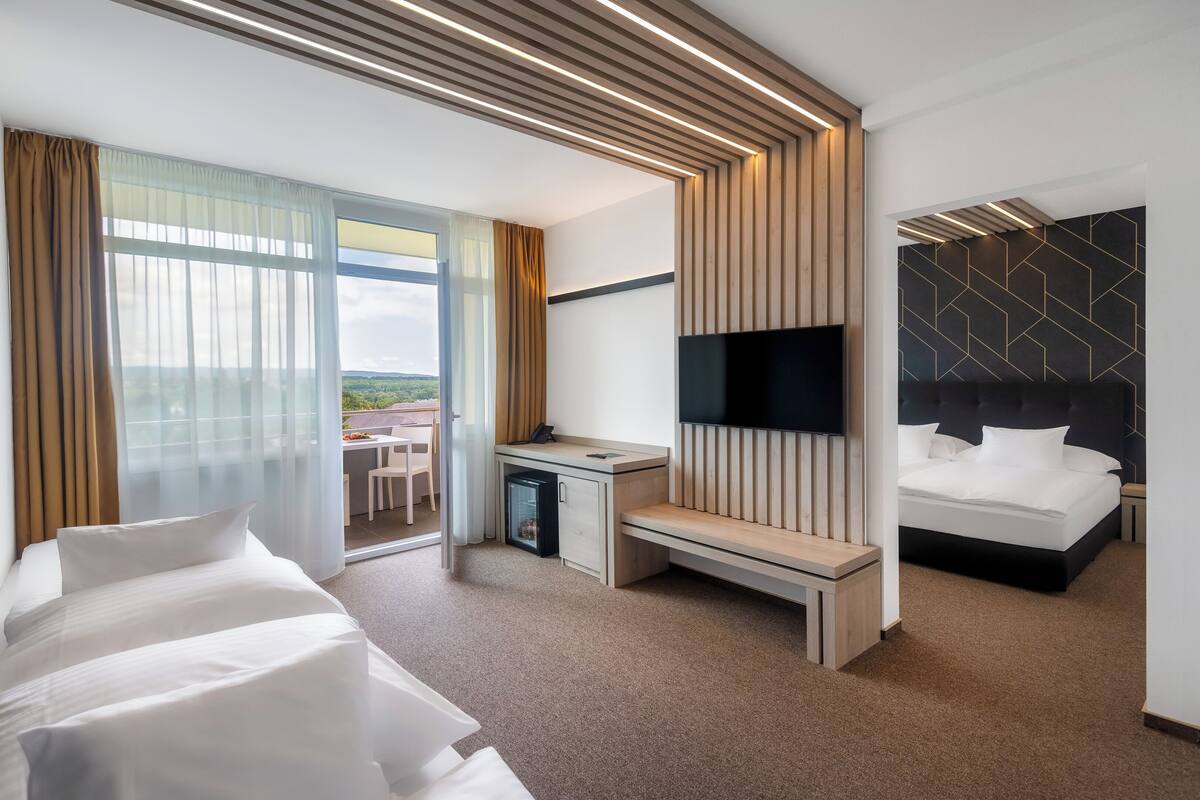 Une chambre d’hôtel moderne équipée d’un lit, d’un bureau, d’une télévision et d’un balcon avec vue.