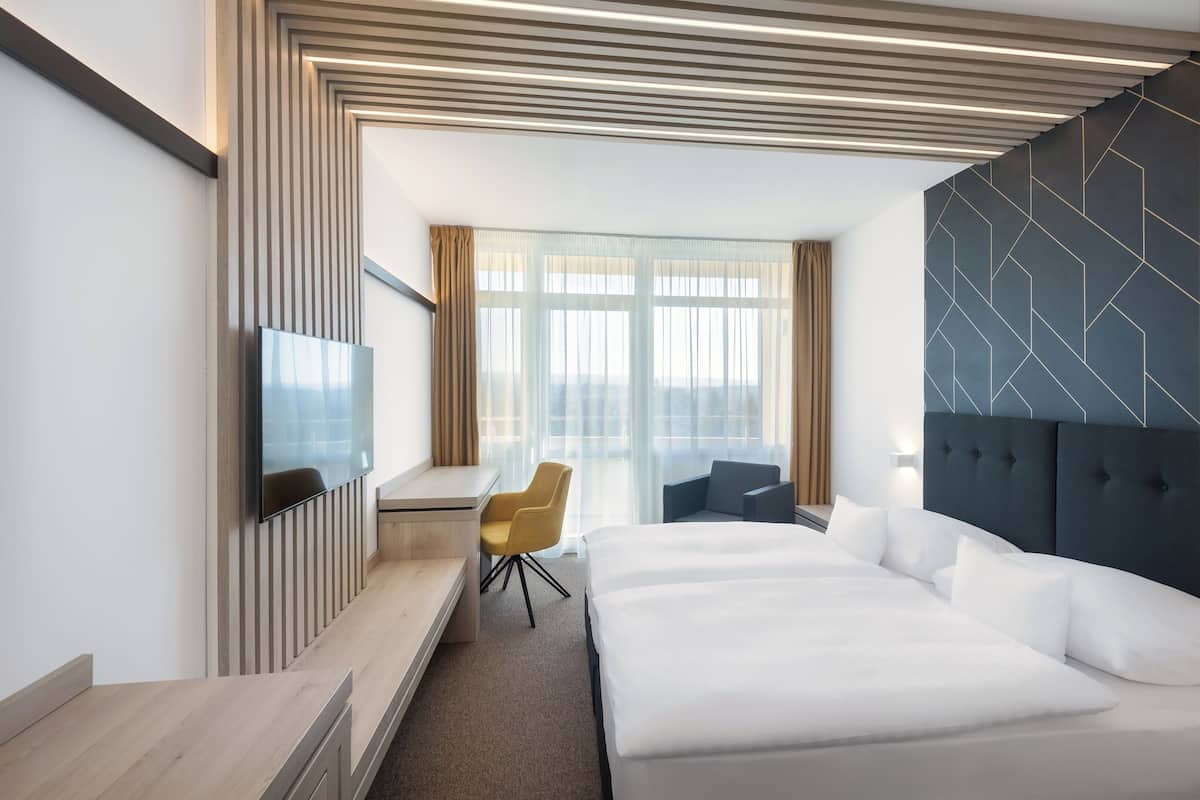 Une chambre d’hôtel moderne équipée d’un grand lit, d’un bureau, d’une chaise et d’un téléviseur.