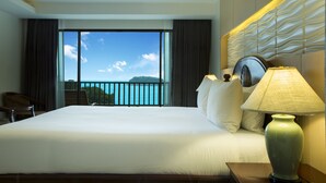 A hotel room with a large bed, a nightstand with a lamp, a chair, and a view of the sea through a balcony. - Chanalai Garden Resort, Kata Beach (Karon)