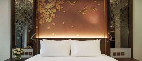A hotel room with a large bed, a decorative headboard, and a nightstand with a vase of flowers.