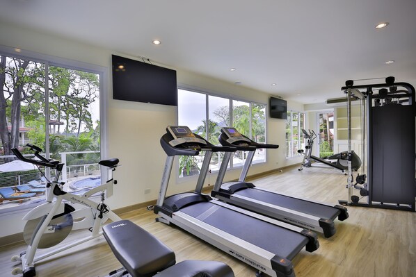 Un gimnasio con cintas de correr, bicicletas estáticas y máquinas de pesas.