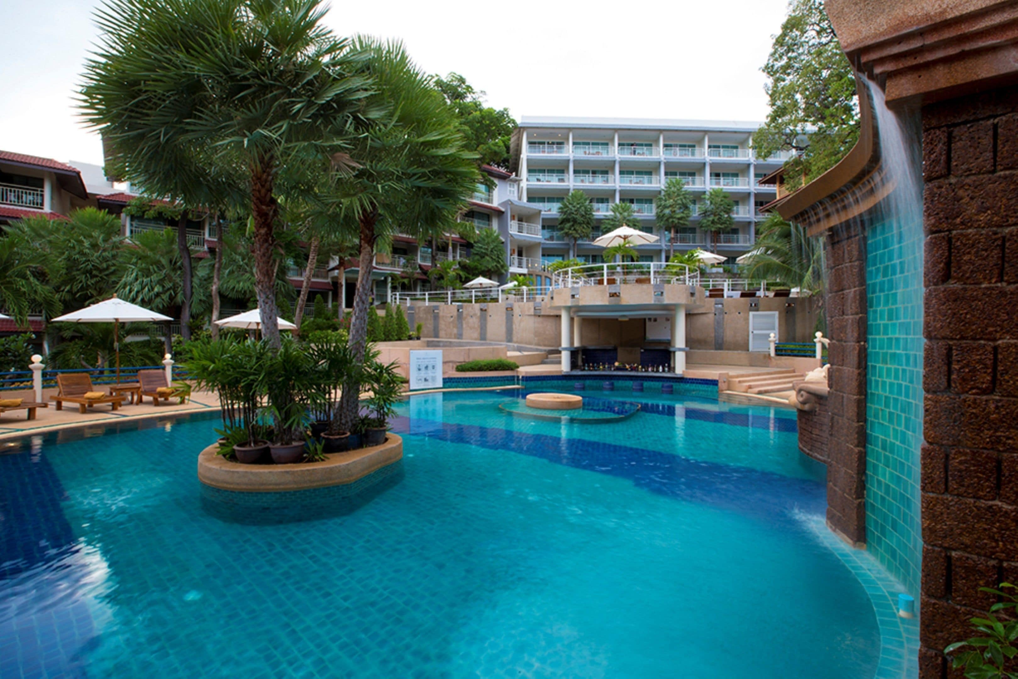 A hotel pool area with multiple levels, palm trees, and lounge chairs.