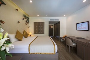 Habitación de hotel con cama, escritorio y televisor.