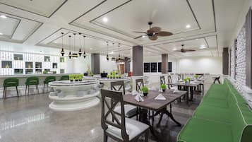 Un restaurante moderno con barra central, asientos verdes y ventiladores de techo.