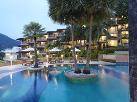 Un hotel con zona de piscina, varios balcones y palmeras.