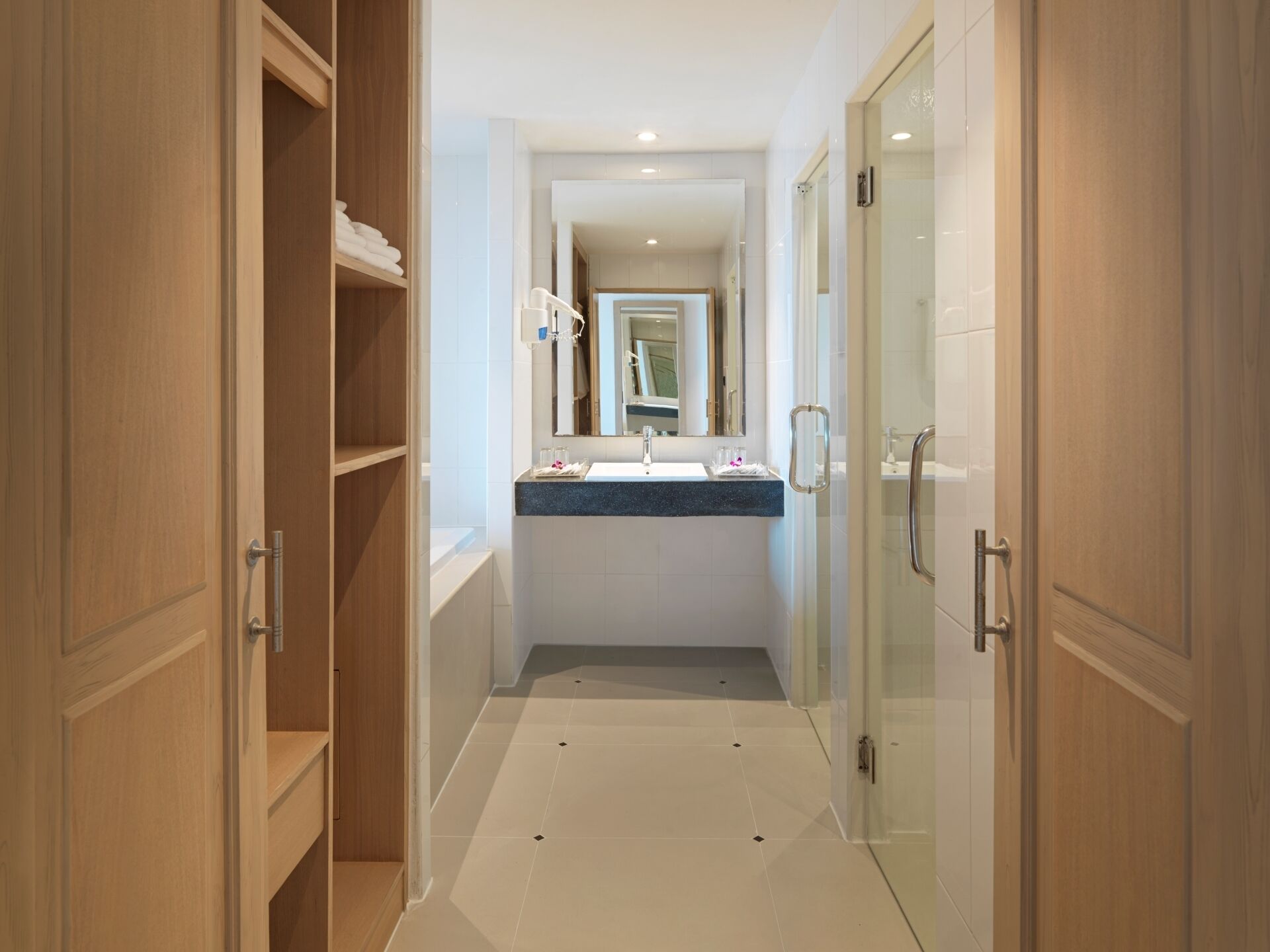 Un baño moderno con cabina de ducha de vidrio, tocador con lavabo y espejo, y muebles de madera.