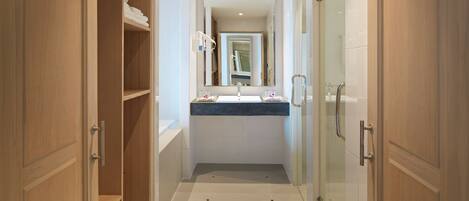 Un baño moderno con cabina de ducha de vidrio, tocador con lavabo y espejo, y muebles de madera.
