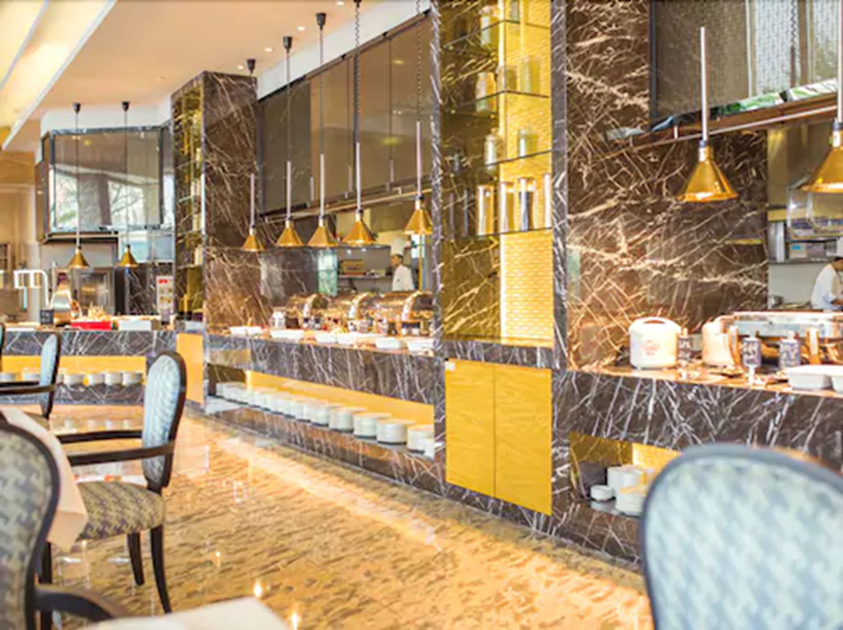 A modern hotel lobby with marble flooring, a reception desk, and seating areas.