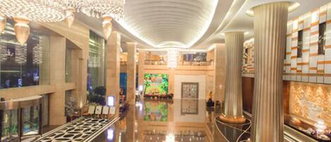 A spacious lobby with a high ceiling, large columns, and a central art piece.