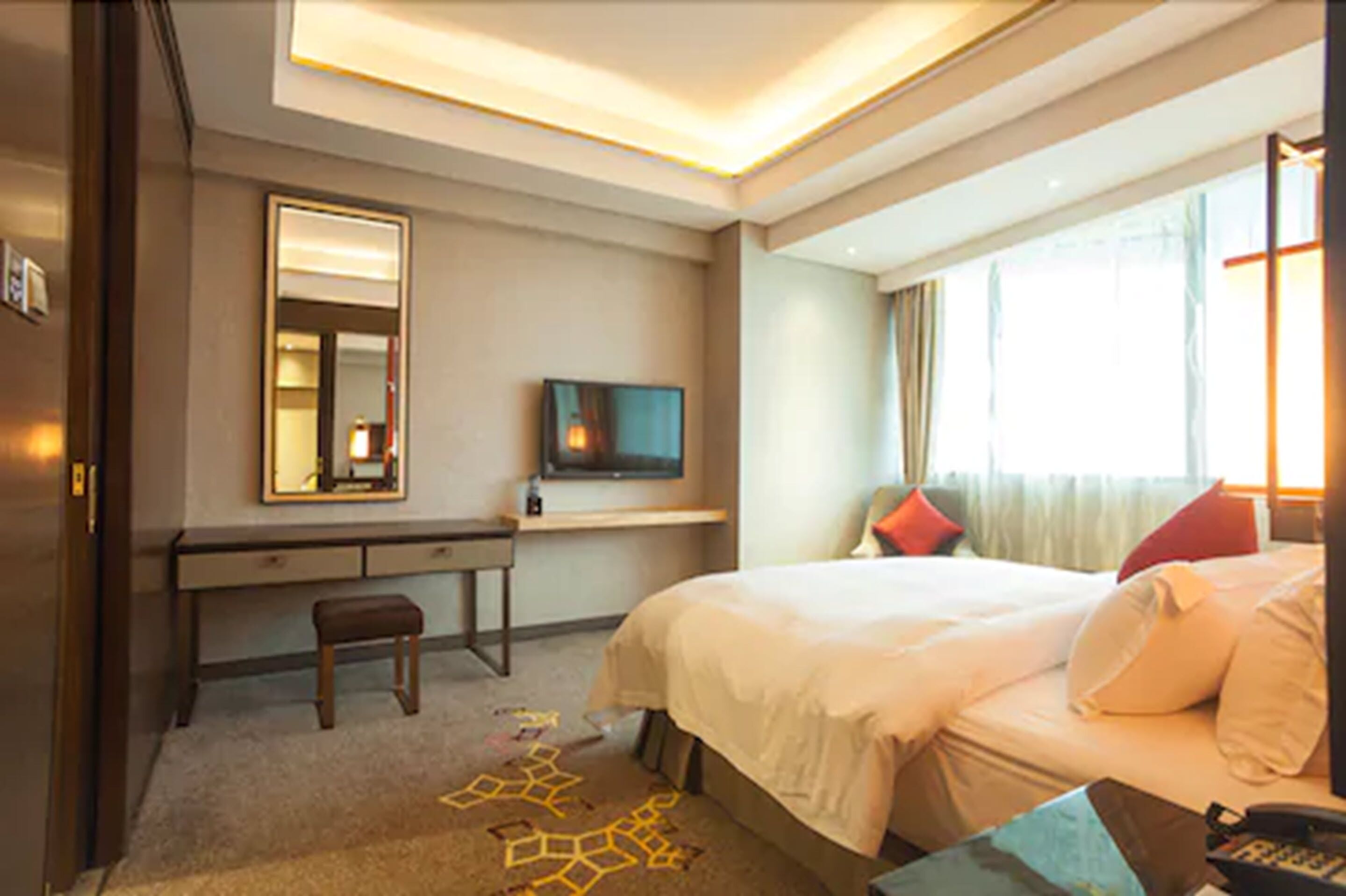 A hotel room with a bed, a desk, a chair, a television, and a window with curtains.