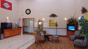 A lobby with a reception desk, seating area, clock, and television. - Days Inn by Wyndham Fordyce (Fordyce)