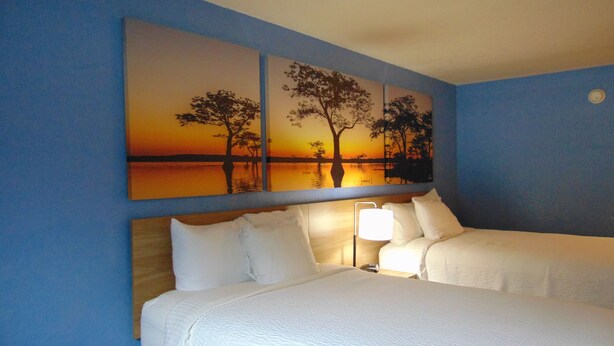 A hotel room with two beds, a nightstand, and a wall-mounted lamp. - Days Inn by Wyndham Fordyce (Fordyce)