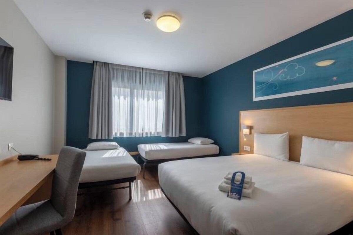 Une chambre d’hôtel avec deux lits, un bureau et une chaise.