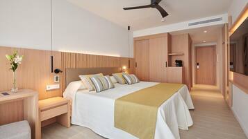 Una habitación de hotel moderna con una cama grande, mesitas de noche, un escritorio, un ventilador de techo y un armario de madera.