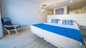 A modern hotel room with a large bed, a rocking chair, a small table, and a wall-mounted TV. - Blau Punta Reina (Manacor)