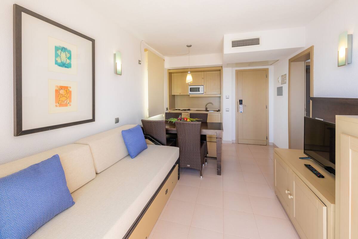 A modern living room with a sofa, a dining table, and a TV.