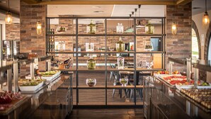 A buffet area with a brick wall, hanging lights, and a variety of food items. - Blau Punta Reina (Manacor)