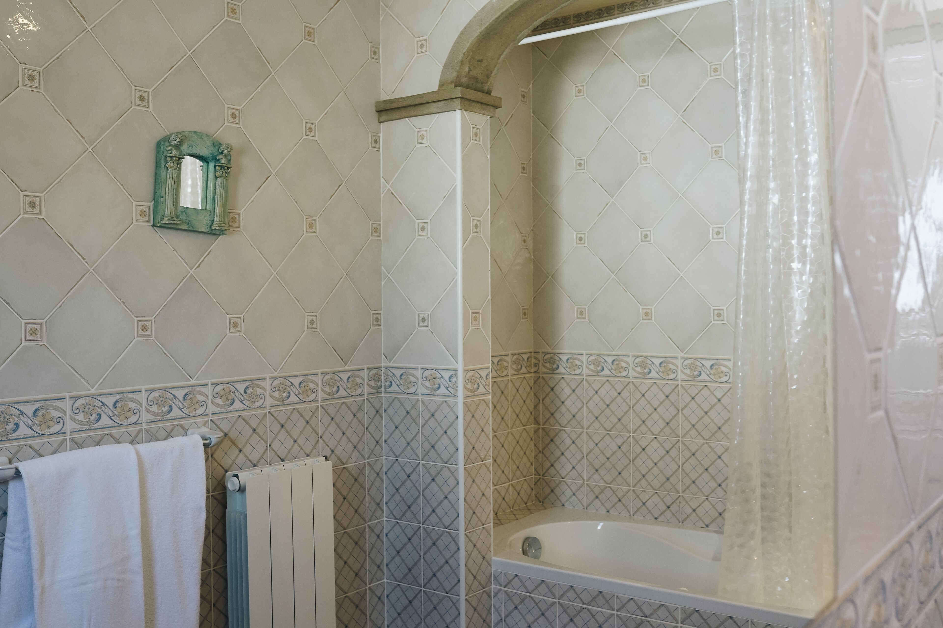 Une salle de bain avec une baignoire, un porte-serviettes et un miroir décoratif.