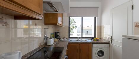 A modern kitchen with a built-in oven, a sink, and a washing machine.