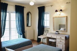 A bedroom with two beds, a dresser, a mirror, and a window with curtains.
