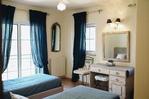 Un dormitorio con dos camas, un tocador, un espejo y una ventana con cortinas.