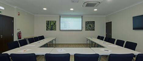 A conference room with a long table, chairs, a projector, and a screen.
