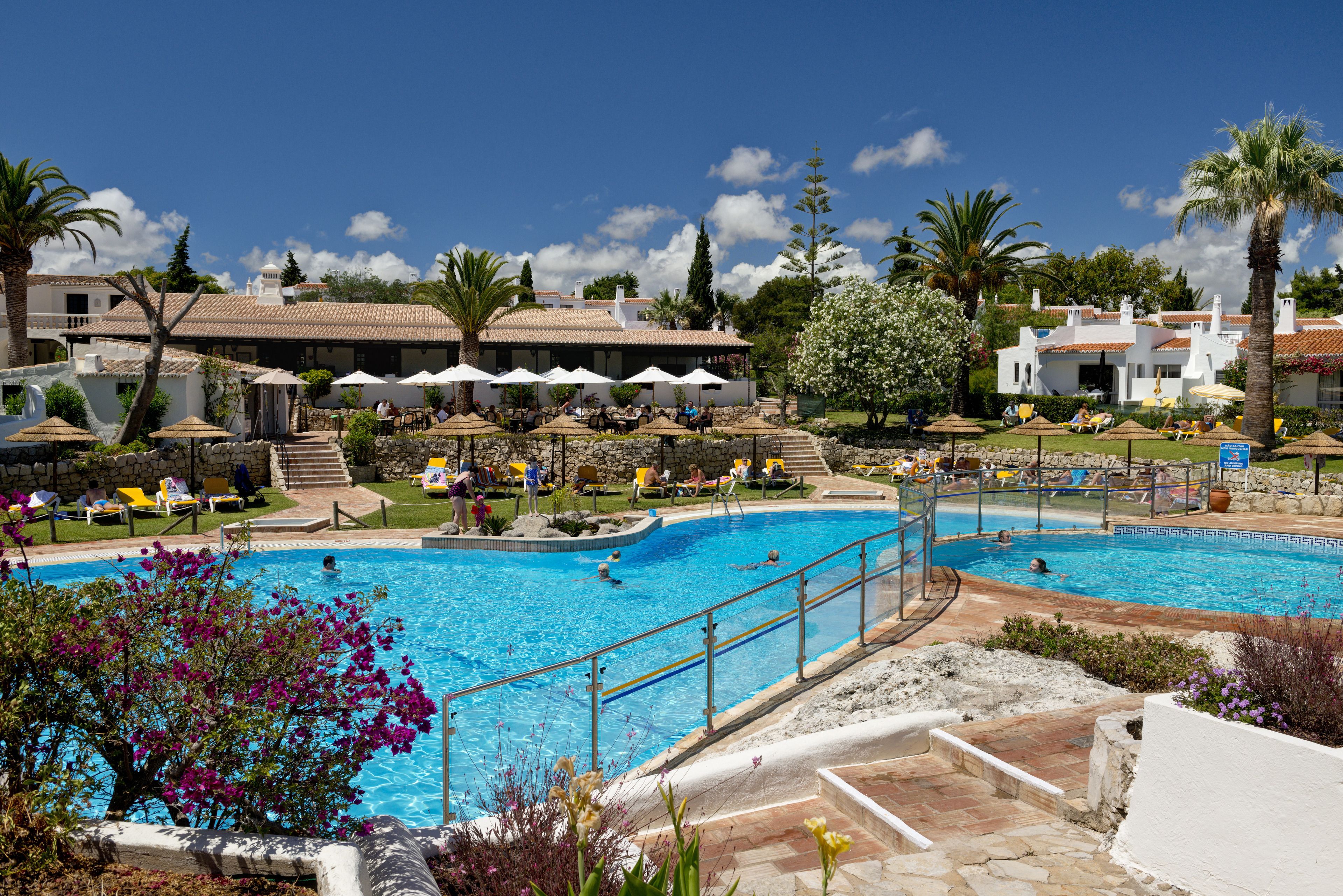 A resort pool area with multiple swimming pools, lounge chairs, and umbrellas.