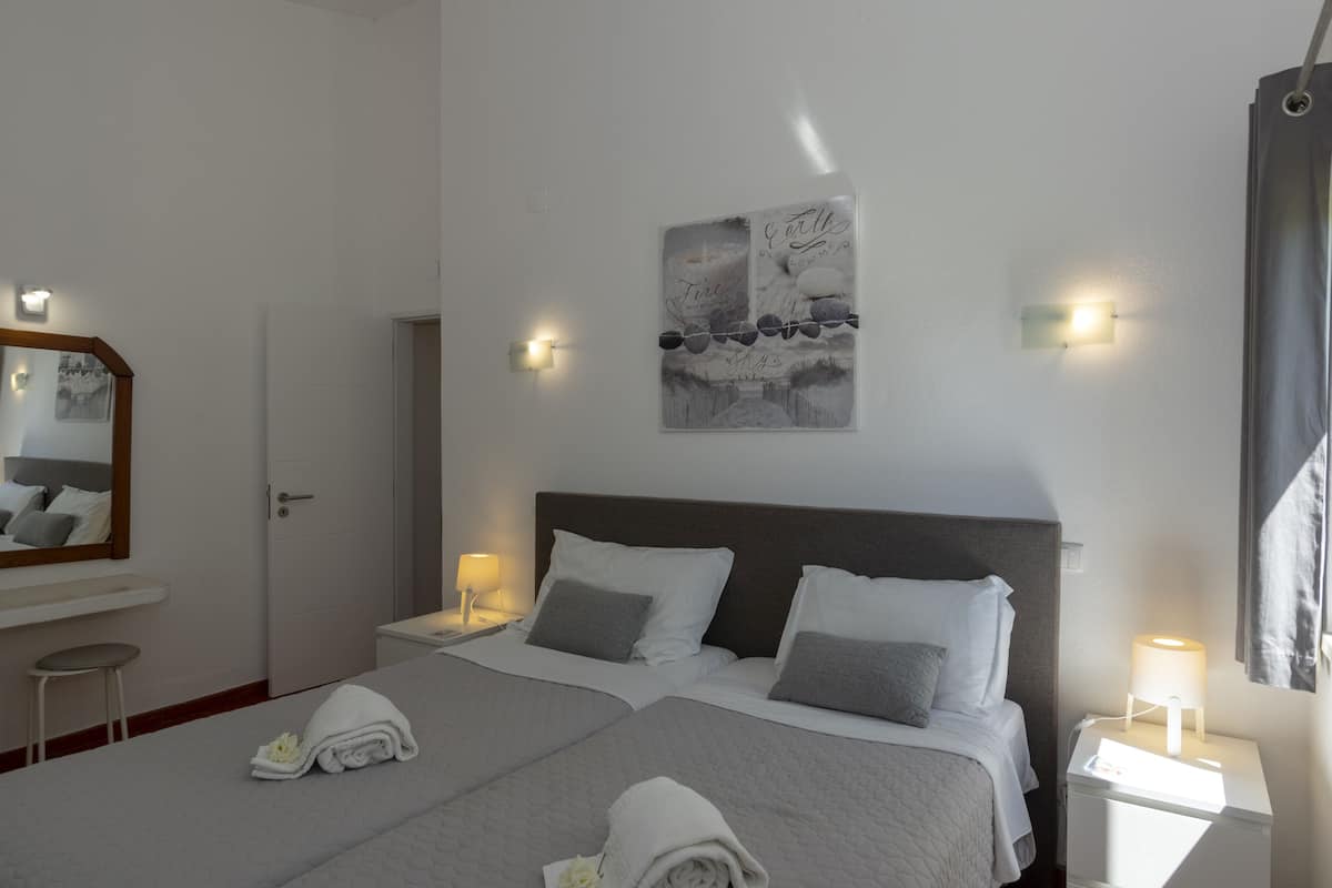 Un lit bien fait, avec des oreillers, une table de chevet avec une lampe, un tableau accroché au mur et un miroir.
