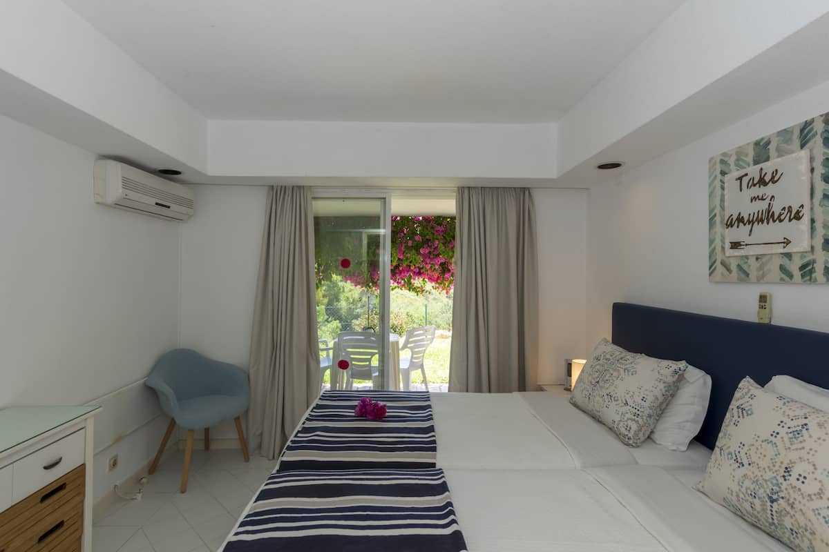 A modern bedroom with a bed, a desk, a chair, and a view of the outdoors.