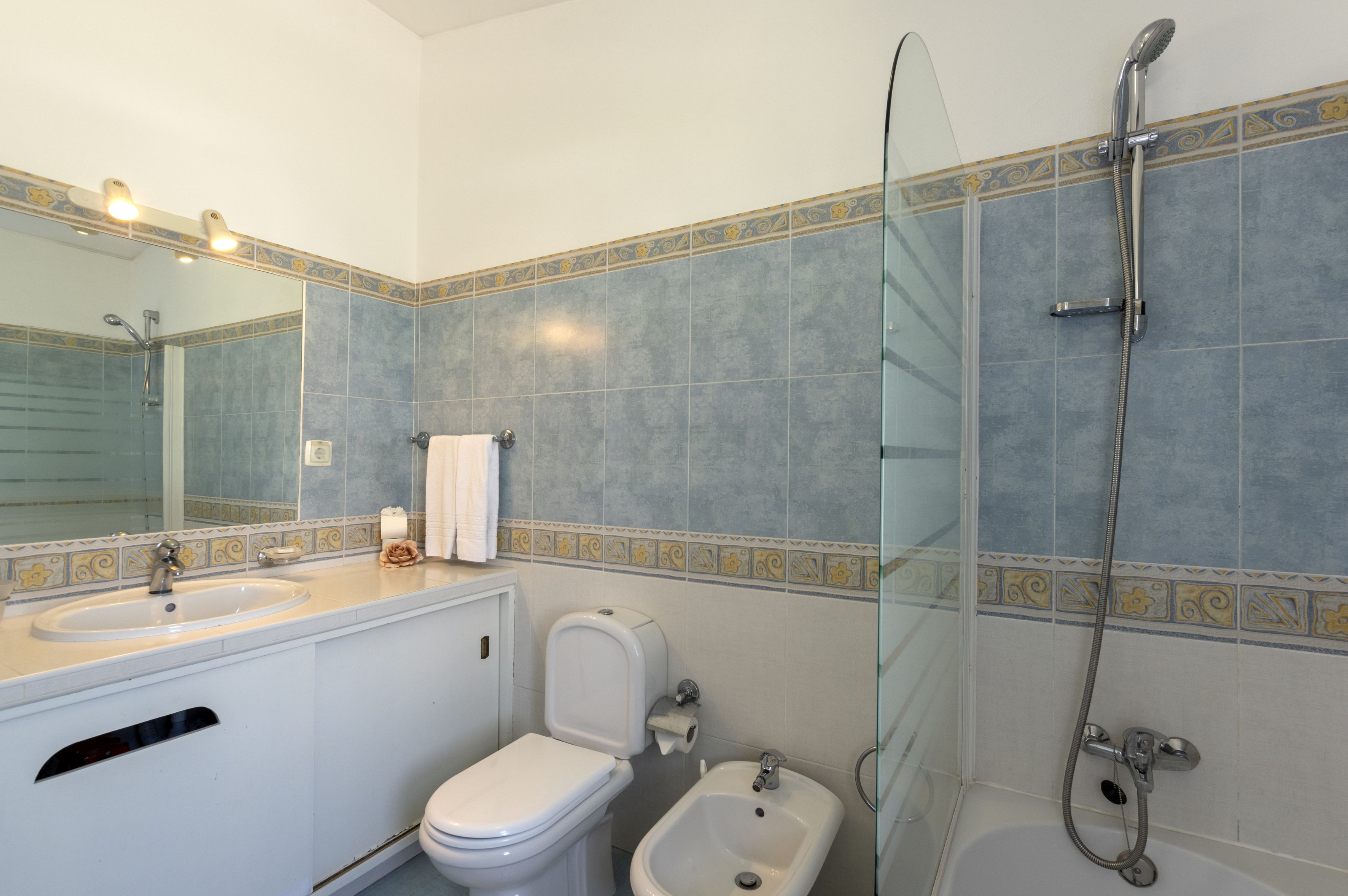 A bathroom with a sink, toilet, bidet, and shower.