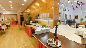 Un buffet avec des présentoirs de nourriture et de boissons, des tables et un espace aménagé pour une scène.