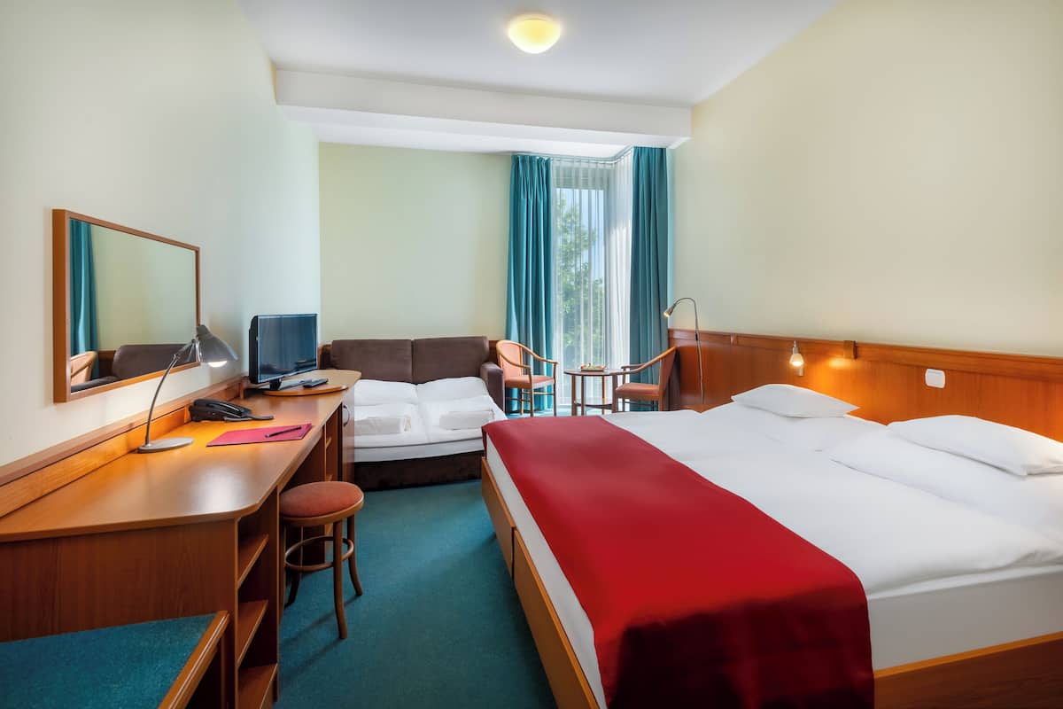 Une chambre d’hôtel équipée d’un bureau, de deux lits, d’une chaise et d’une petite table.