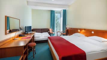 Een hotelkamer met een bureau, twee bedden, een stoel en een klein tafeltje.
