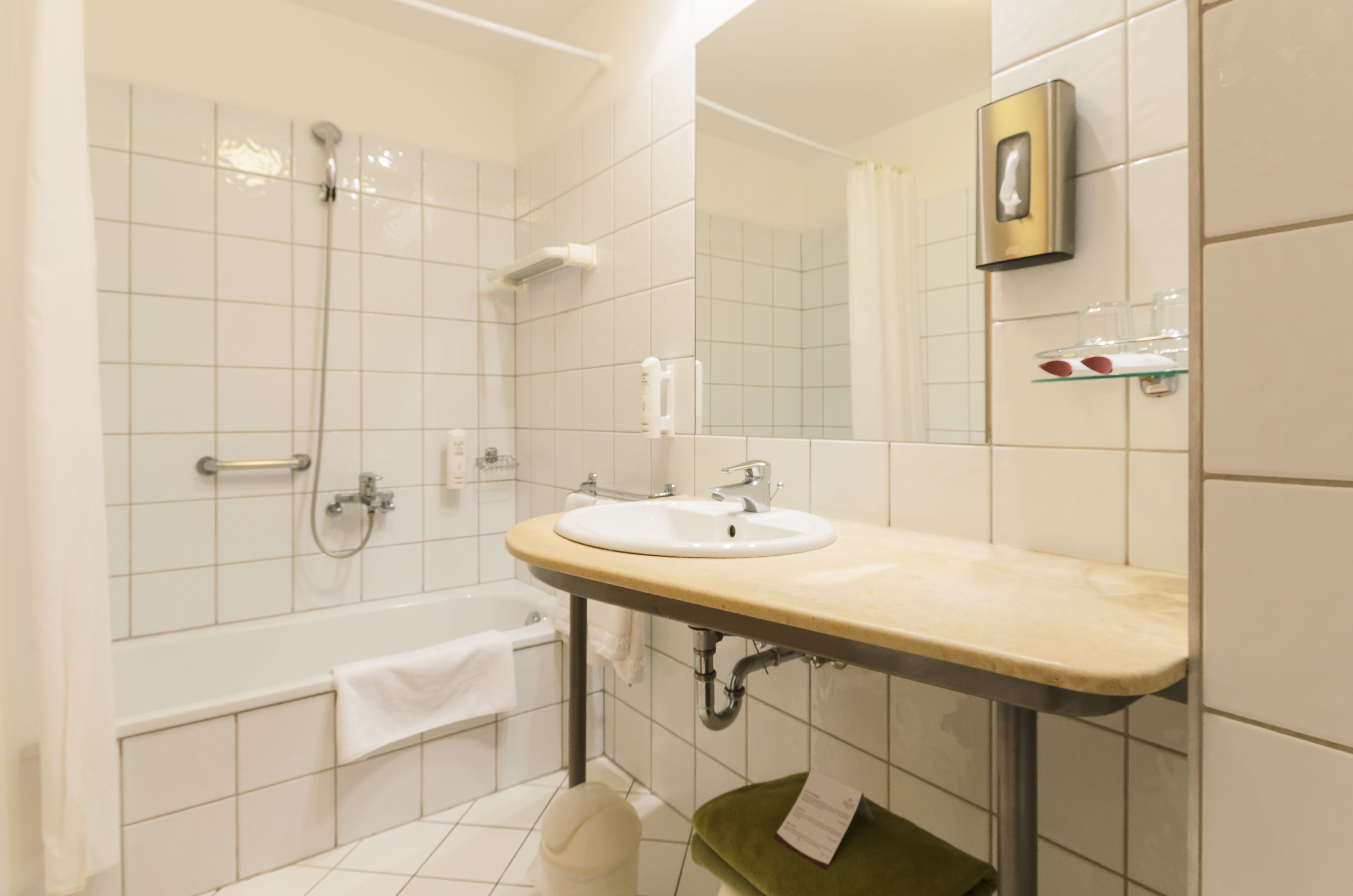 A bathroom with a bathtub, a sink, and a mirror.