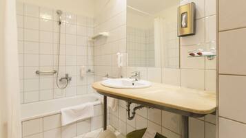 A bathroom with a bathtub, a sink, and a mirror.