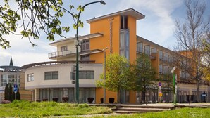 Un bâtiment moderne à la façade jaune, sur lequel on peut lire l’inscription « HUNGEESTHO », et un panneau indiquant un parking, avec la mention « P ».