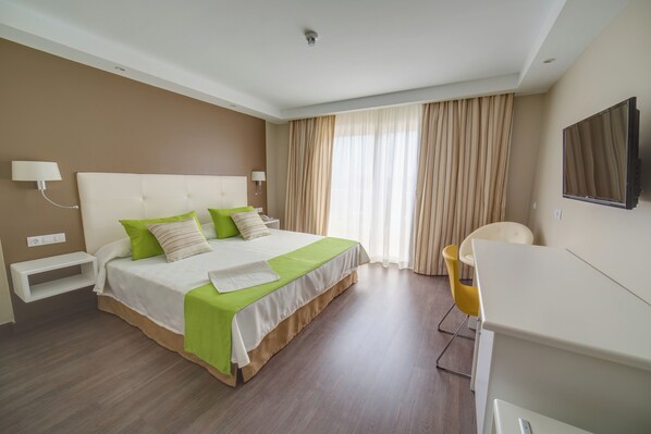 Ein modernes Hotelzimmer mit einem großen Bett, einem Schreibtisch und einem Fernseher.
