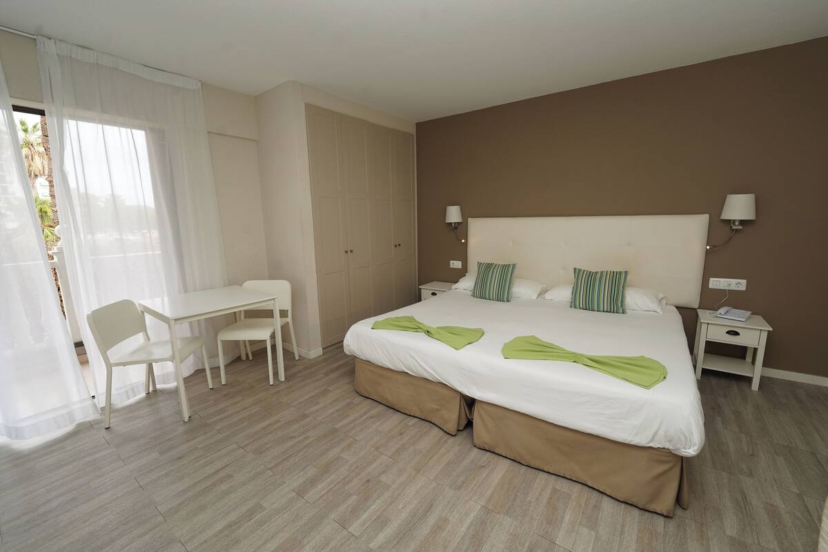 A hotel room with a bed, a desk, and a chair.