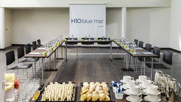 Un salón de conferencias con una mesa larga, sillas y un cartel que dice "H10 blue mar".