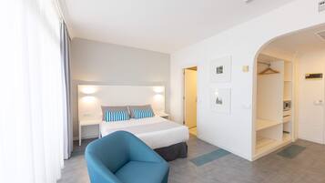 Habitación de hotel con cama, mesitas de noche, una silla, armario y puerta al baño.