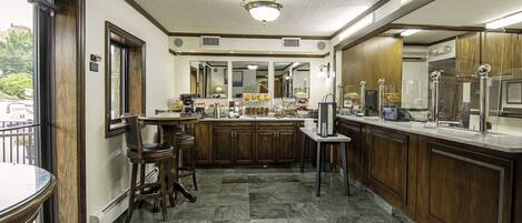 A kitchen with wooden cabinets, a marble floor, and a bar area with stools.